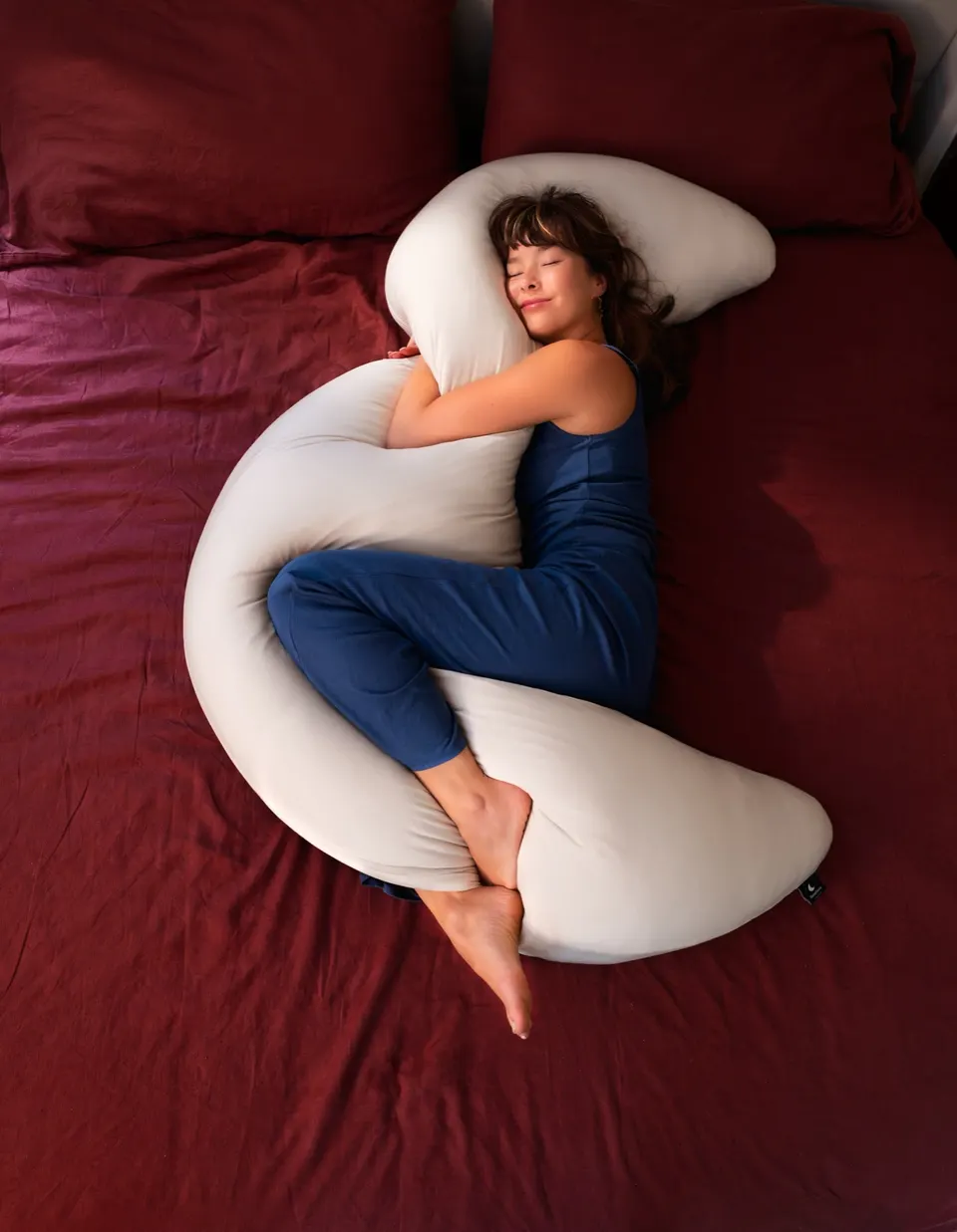 Asleep on her side hugging the MoonSpoon on red sheets