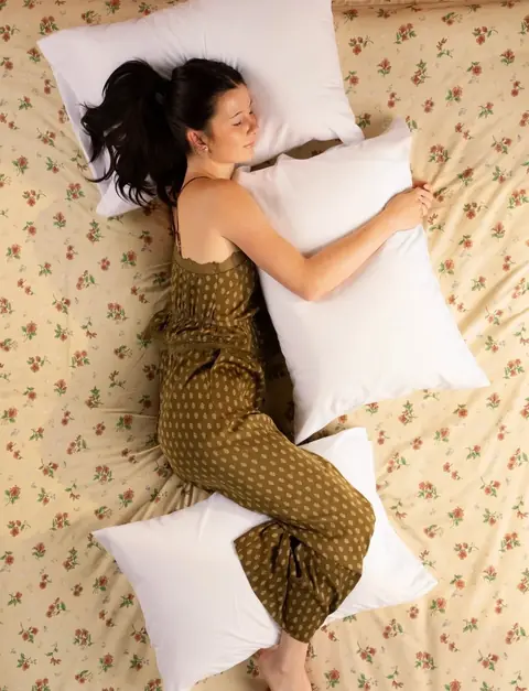 Lying on her side between four regular pillows