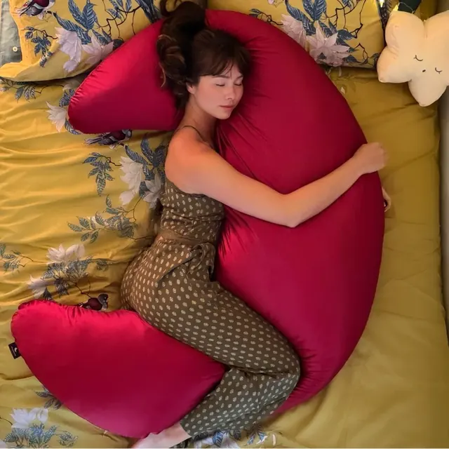 Sleeping hugging the MoonSpoon™ body pillow in a red cover